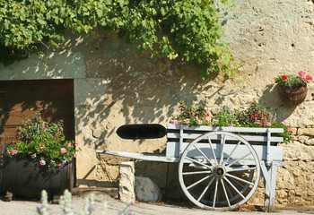 Une charrette bleue et fleurie  devant une ferme
