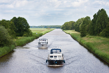 Two yachts sailing in a straight Dutch canal
