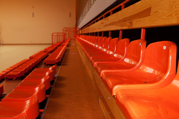 Orange, plastic seats in rows at sport indoor arena.