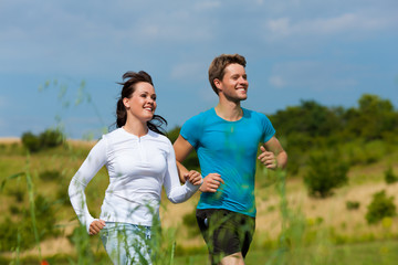 Fototapeta premium Young sportive couple is jogging outside