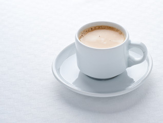 Coffee cup on white tablecloth
