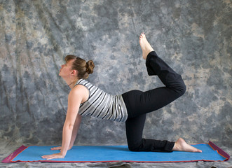 woman doing Yoga posture Vyaghrasana The Tiger Pose