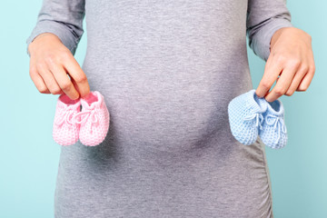 Pregnant woman holding baby booties - 33749824