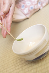 抹茶を茶碗に入れる女性の手元