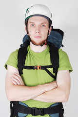 mountain tourist in helmet and with big backpack standing with c