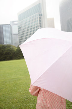 傘をさして公園に立つ女性の後姿