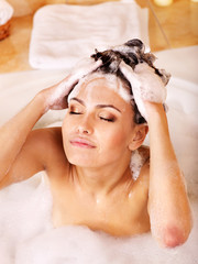 Woman washing hair by shampoo .