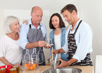 Family preparing fruit jam in home kitchen