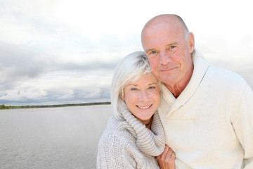 Portrait of happy senior couple standing by a lake