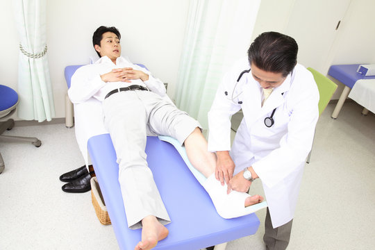 患者の足に包帯を巻く医者