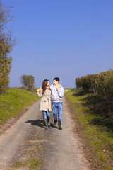 Fototapeta premium Couple of young people walking in the campaign in spring