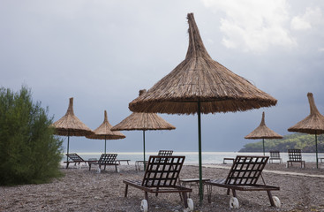 Straw Umbrellas with Sun Loungers on Beach