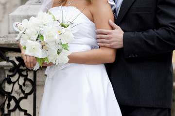 Obraz na płótnie Canvas bride and groom's hands holding wedding bouquet