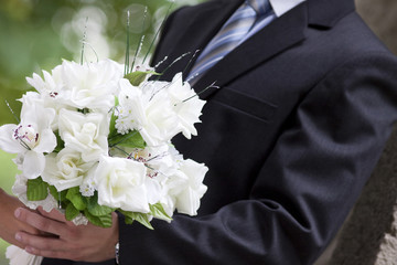 bride and groom's hands holding wedding bouquet