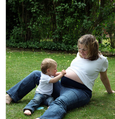 Fototapeta premium Pregnant woman sitting with her child in garden