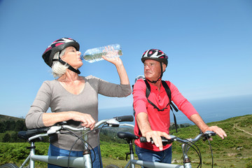 Senior couple drinking water during bike ride