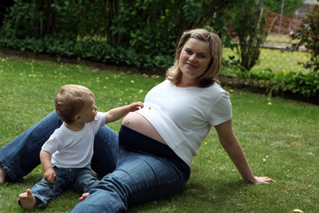 Fototapeta premium Pregnant woman sitting with her child in garden