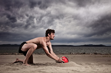 strong sexy male with red ball on the beach