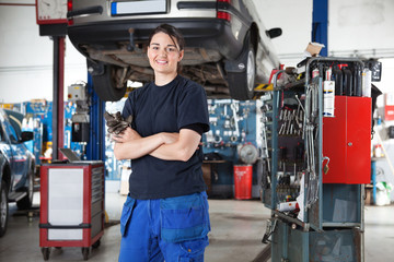 Smiling young female mechanic in garage