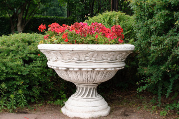 Белая  ваза с цветами в саду.