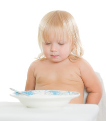 Adorable toddler girl eat porridge with spoon from plate