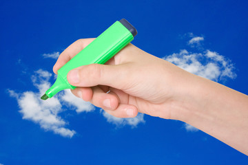 hand with a marker over a blue sky background.