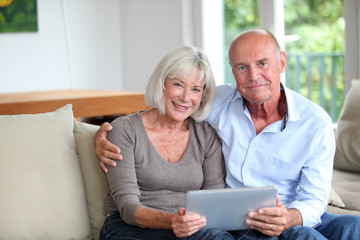 Senior couple using electronic tablet at home