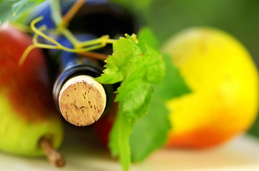 Bottle of wine and fruit with grapevine leves.