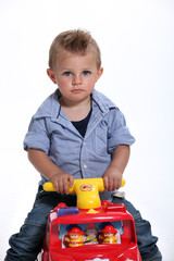 Young boy riding a toy fire engine