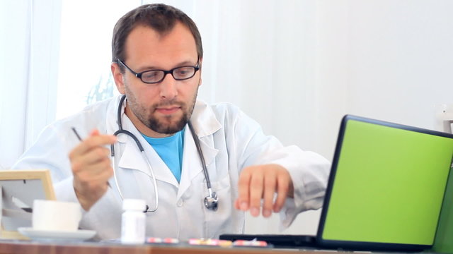 Male doctor looking at medications and writing rx prescription