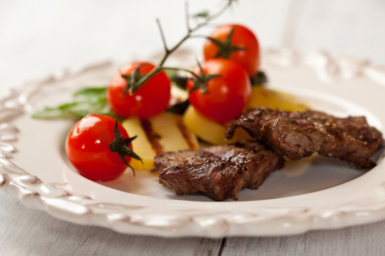 Rustic grilled beef dish with cherry tomatoes and potatoes