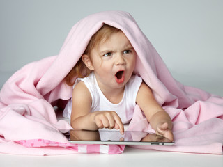Portrait of shouting little girl playing with touchpad