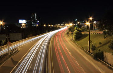 Moving vehicles create light trails along a highway at night