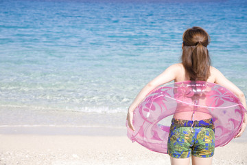 浮輪を持って海に入ろうとしている女性の後ろ姿