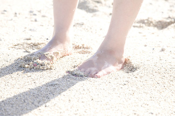 Obraz na płótnie Canvas 砂浜に立つ女性の足元