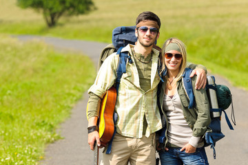 Hiking young couple backpack tramping asphalt road