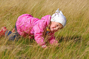 Little girl playing hide and seek in the tall grass.