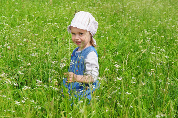 Child sitting in the grass among the wildflowers.