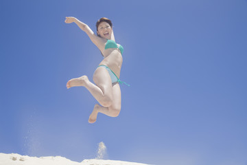 浜辺でジャンプする水着を着た2人の女性の後ろ姿 Wall Mural Paylessimages