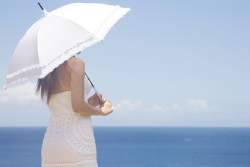 日傘を差して海を眺める女性の斜め後ろ姿