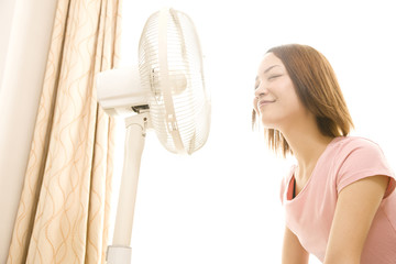 扇風機の風で涼む女性