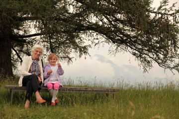 Oma und Enkelin sitzen auf einer Bank