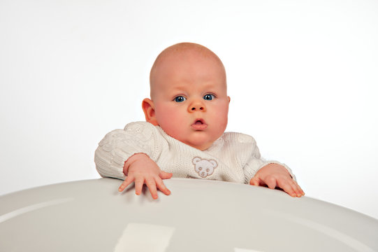Baby watching you from behind the table