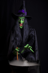 Witch stirring her cauldron, black background.