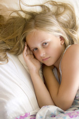 Fototapeta premium Portrait of little girl lying in her bed