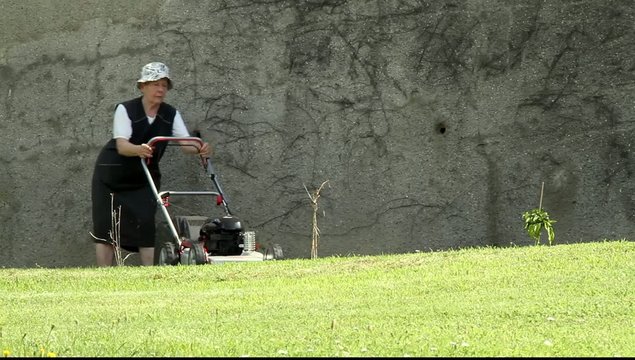 R&uuml;stige betagte Dame beim Rasenm&auml;hen