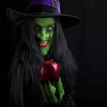 Witch and her red poison apple, dark background.
