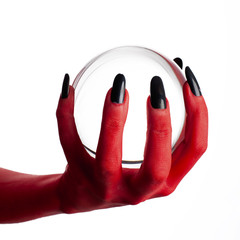 Red hand of devil holding a crystal ball, white background.