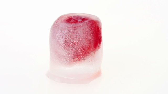 One raspberry berry inside of melting ice cube, time lapse