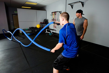 Workout with a rope in a gym with a trainer